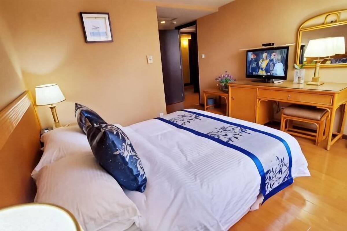 A hotel room with a bed, a desk, a television, and a mirror.