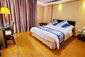 A hotel room with a bed, a desk with a chair, a lamp, and a curtain. - Hedong Hotel (Shenzhen)