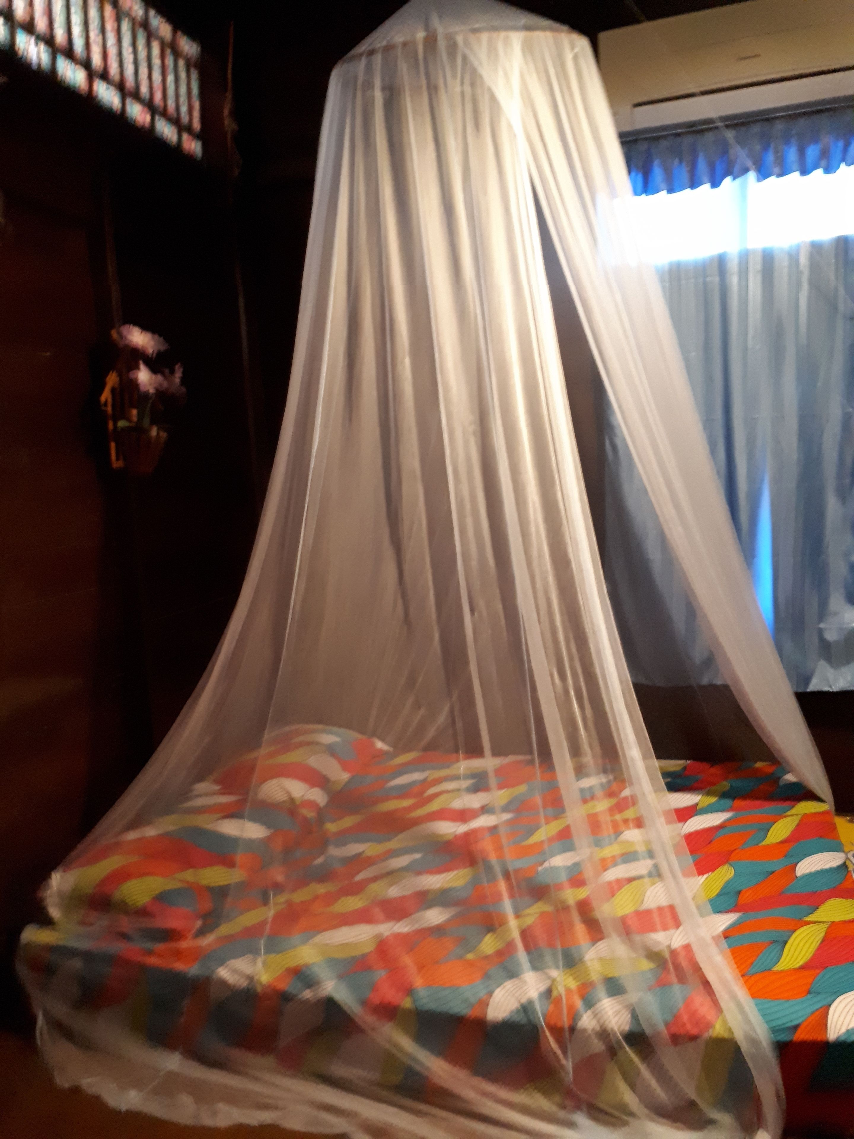 A bed with a colorful quilt and a white canopy.
