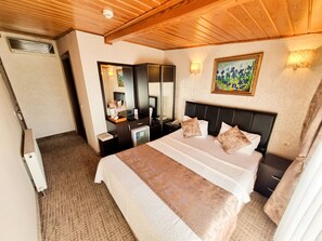 A hotel room with a large bed, a dresser, a mirror, and a painting on the wall. - Eskibağ Butik Hotel (Adalar)
