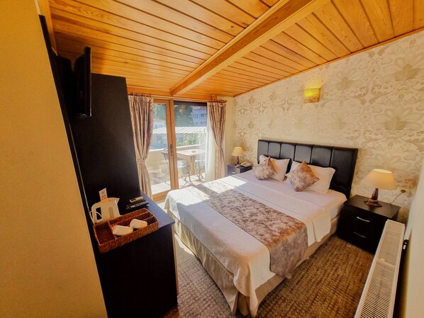 Habitación de hotel con cama, mesitas de noche, escritorio y vistas al exterior.
