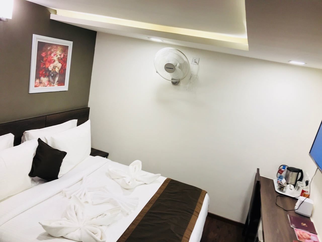 Habitación de hotel con una cama bien hecha, una mesita de noche con cafetera y un aire acondicionado instalado en la pared.