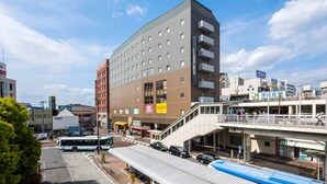 A multi-story hotel with a modern design, featuring a covered bus station and various commercial establishments on the ground floor.
