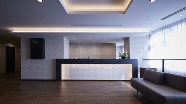 A modern reception area with a brick wall, a reception desk, a sofa, and a large window.