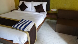 A hotel room with a bed, a chair, and a nightstand. - Aquays Hotels & Resorts (Port Blair)