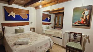 Un dormitorio con una cama grande, dos mesitas de noche, una silla y obras de arte en las paredes.