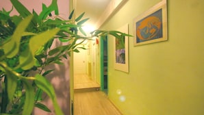 Un pasillo estrecho con suelo de madera, pared verde y una obra de arte enmarcada.