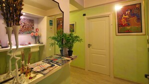 Un pasillo con una mesa de recepción, una planta en maceta y una puerta.