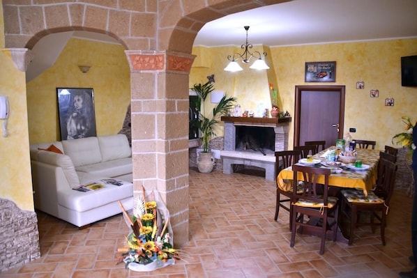 A dining area with a stone fireplace, a white sofa, and a dining table set for four.
