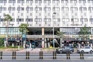 Un bâtiment moderne dont le rez-de-chaussée abrite plusieurs commerces, notamment un salon de coiffure et un restaurant.