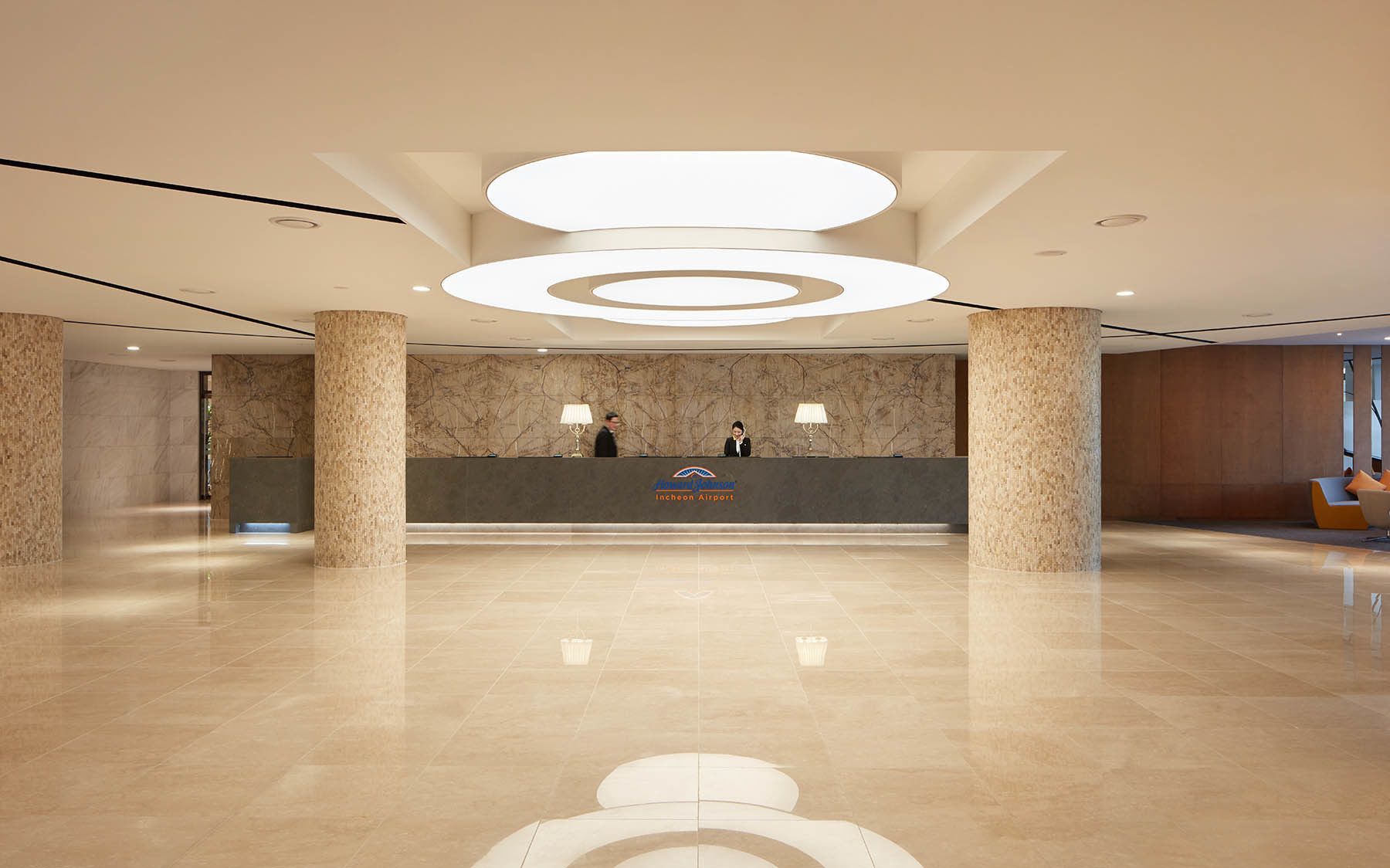 Um hall de hotel moderno com uma mesa de recepção, colunas de mármore e piso limpo e lustroso.