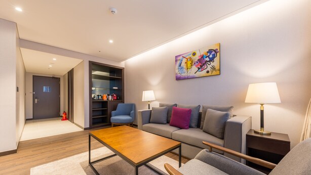 A modern living room with a sofa, armchairs, a coffee table, and a bookshelf. - Howard Johnson by Wyndham Incheon Airport (Incheon)