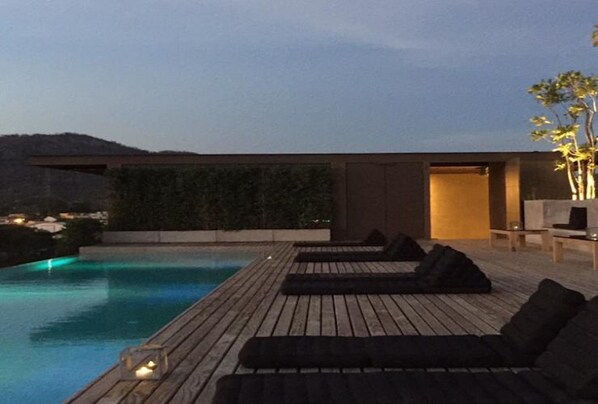 A modern outdoor pool area with wooden decking and lounge chairs.