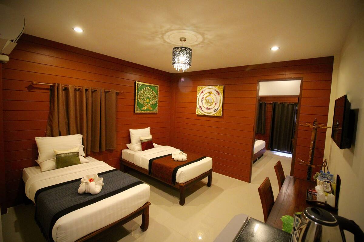 A hotel room with two beds, a dining table, and a chandelier.