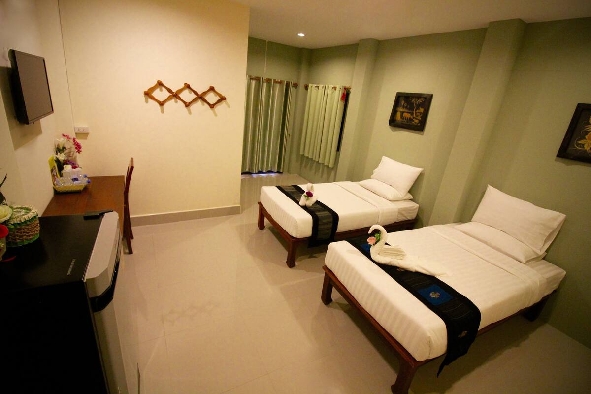 A hotel room with two beds, a desk, and a chair.