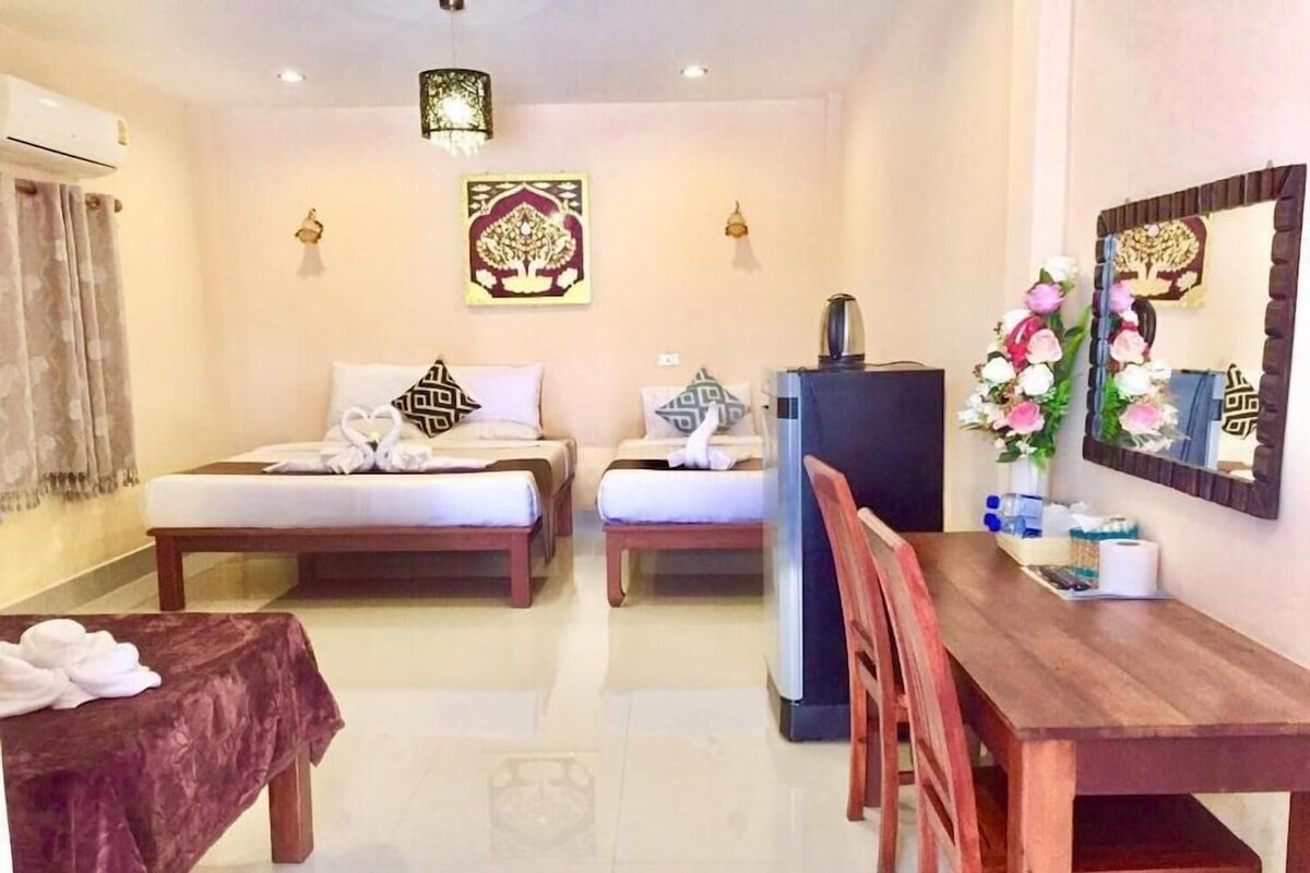 Habitación de hotel con dos camas, una mesa de comedor y un refrigerador.