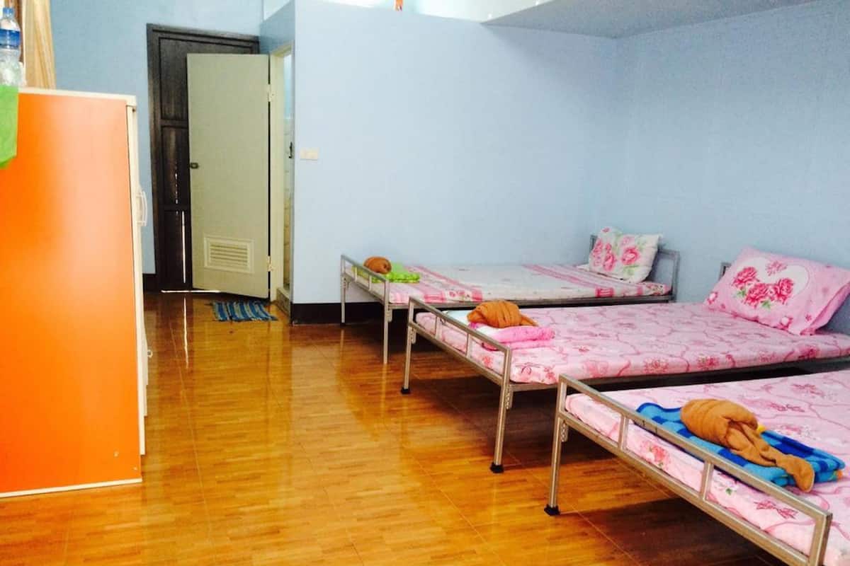 Habitación tipo dormitorio con tres literas, suelo de madera y una puerta que da a otra habitación.
