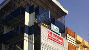 Un edificio de varios pisos con señalización comercial, incluyendo un llamativo cartel rojo y un letrero azul sobre la entrada.