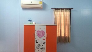 Una habitación con suelo de madera, un armario rojo y blanco con diseño de corazón, una ventana con cortinas y un aire acondicionado en la pared.