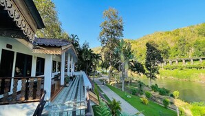 A traditional building with a balcony, a river view, and a bridge in the background. - Baan Rim Kwai Paerimnam Resort (Sai Yok)