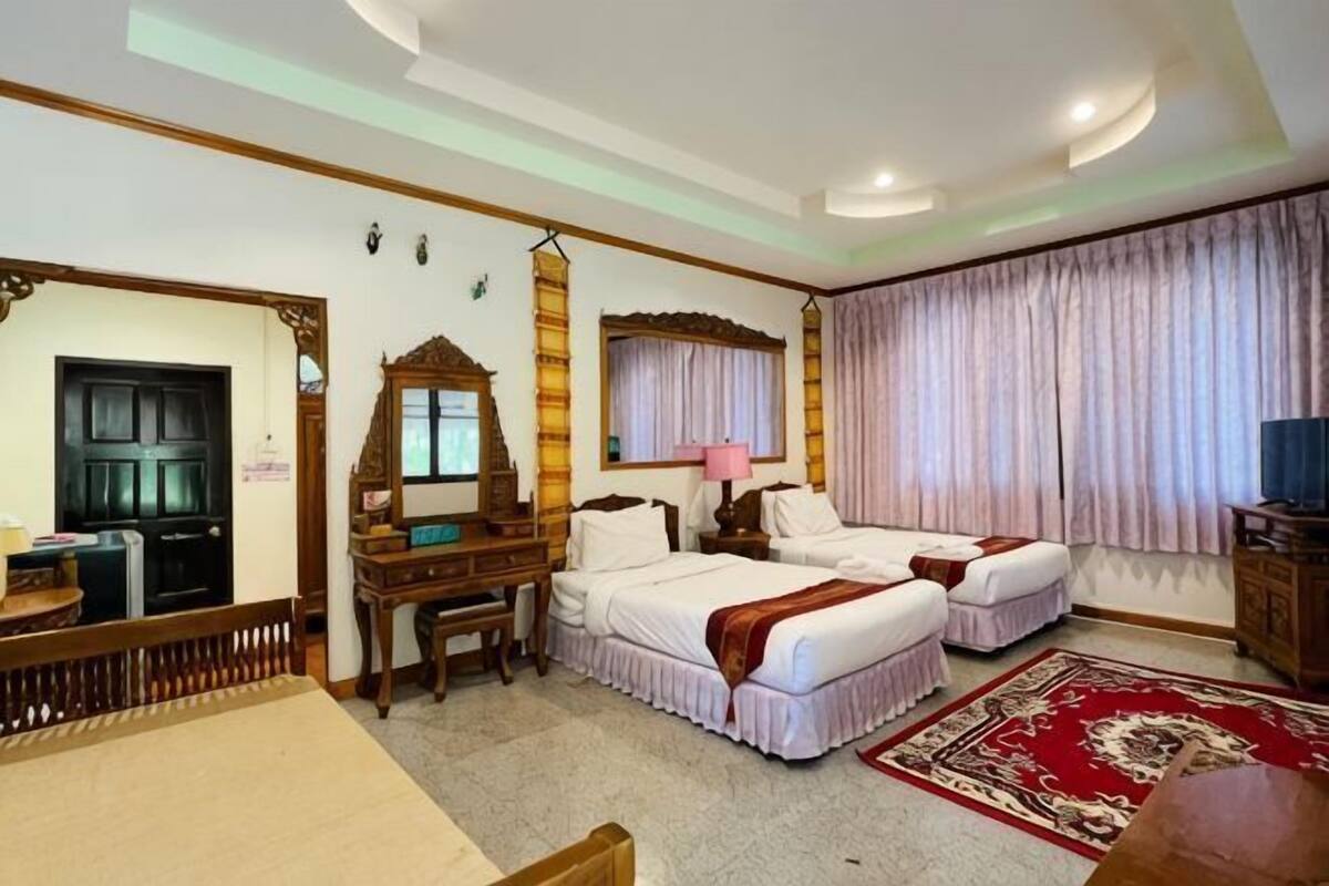 A hotel room with two beds, a desk, a chair, a mirror, and a television.