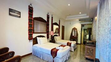 A hotel room with two beds, a wooden headboard, a mirror, a small table, and a cabinet.