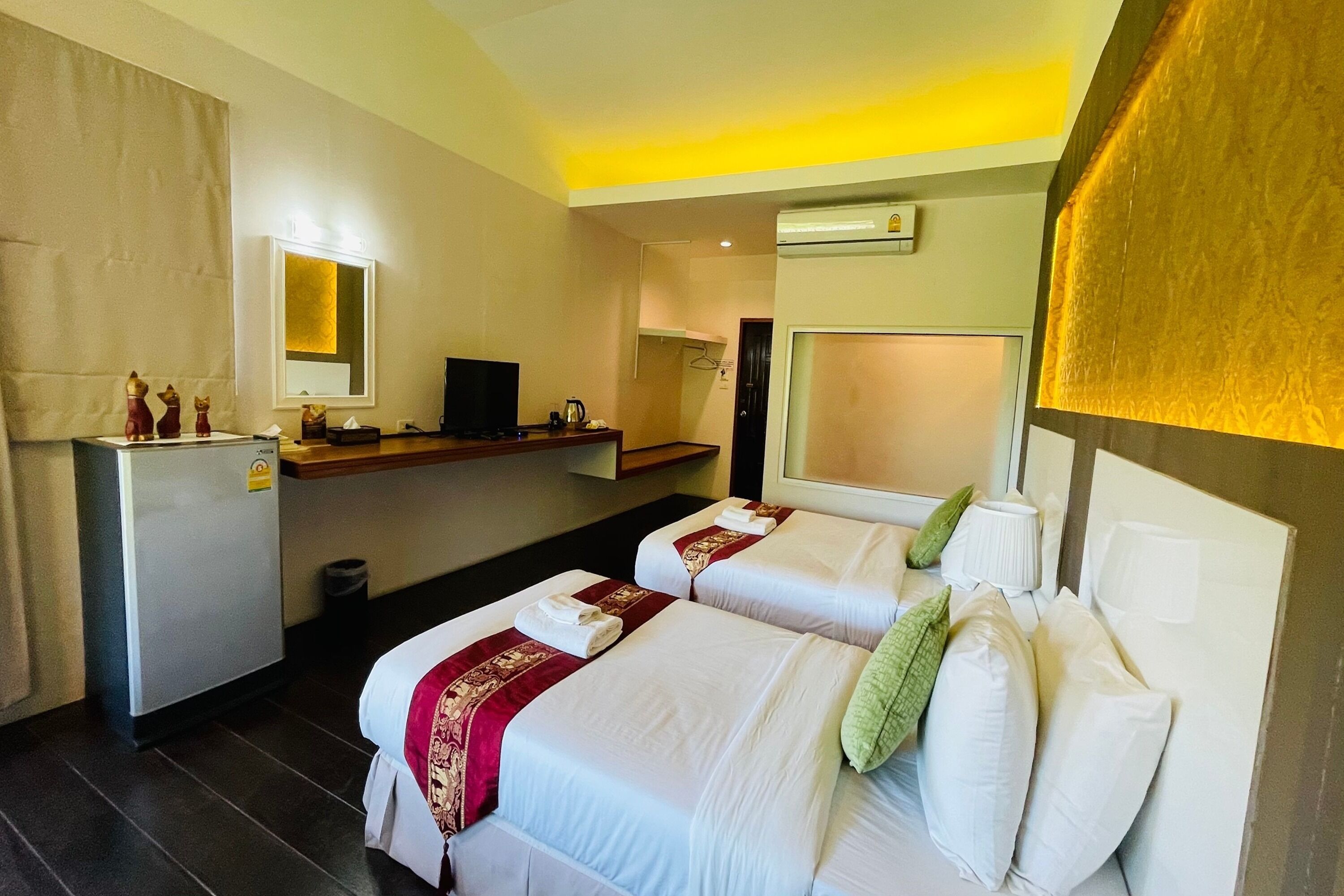 Una habitación de hotel con dos camas, una kitchenette pequeña, un espejo y un televisor.