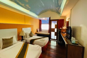 Ein Hotelzimmer mit zwei Betten, einem Schreibtisch mit Fernseher und Blick zum Himmel durch ein Fenster.