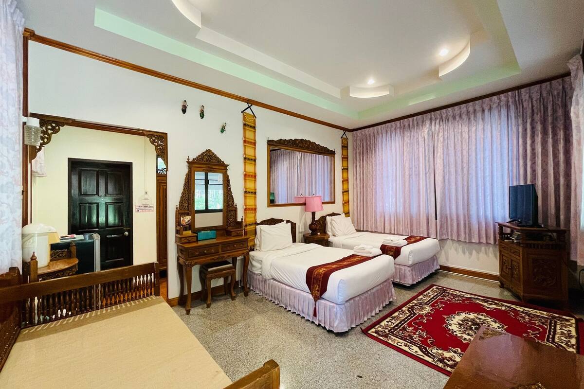 A hotel room with two beds, a desk, a chair, a TV, and a large mirror.