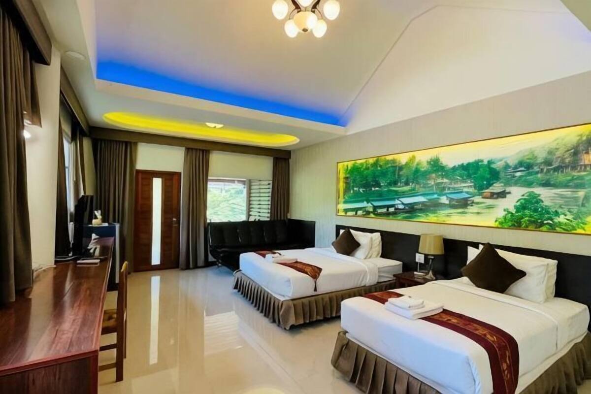 A hotel room with two beds, a desk, a TV, and a large painting of a landscape.