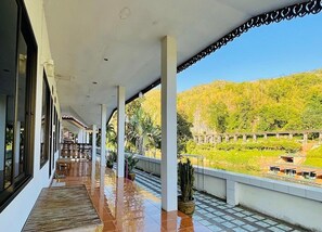 Ein überdachter Balkon mit Blick auf einen angelegten Garten und eine Brücke.