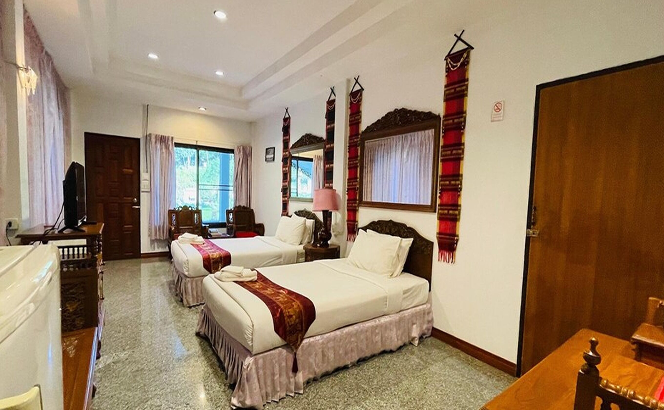 Habitación de hotel con dos camas, televisión, escritorio y ventana con cortinas.