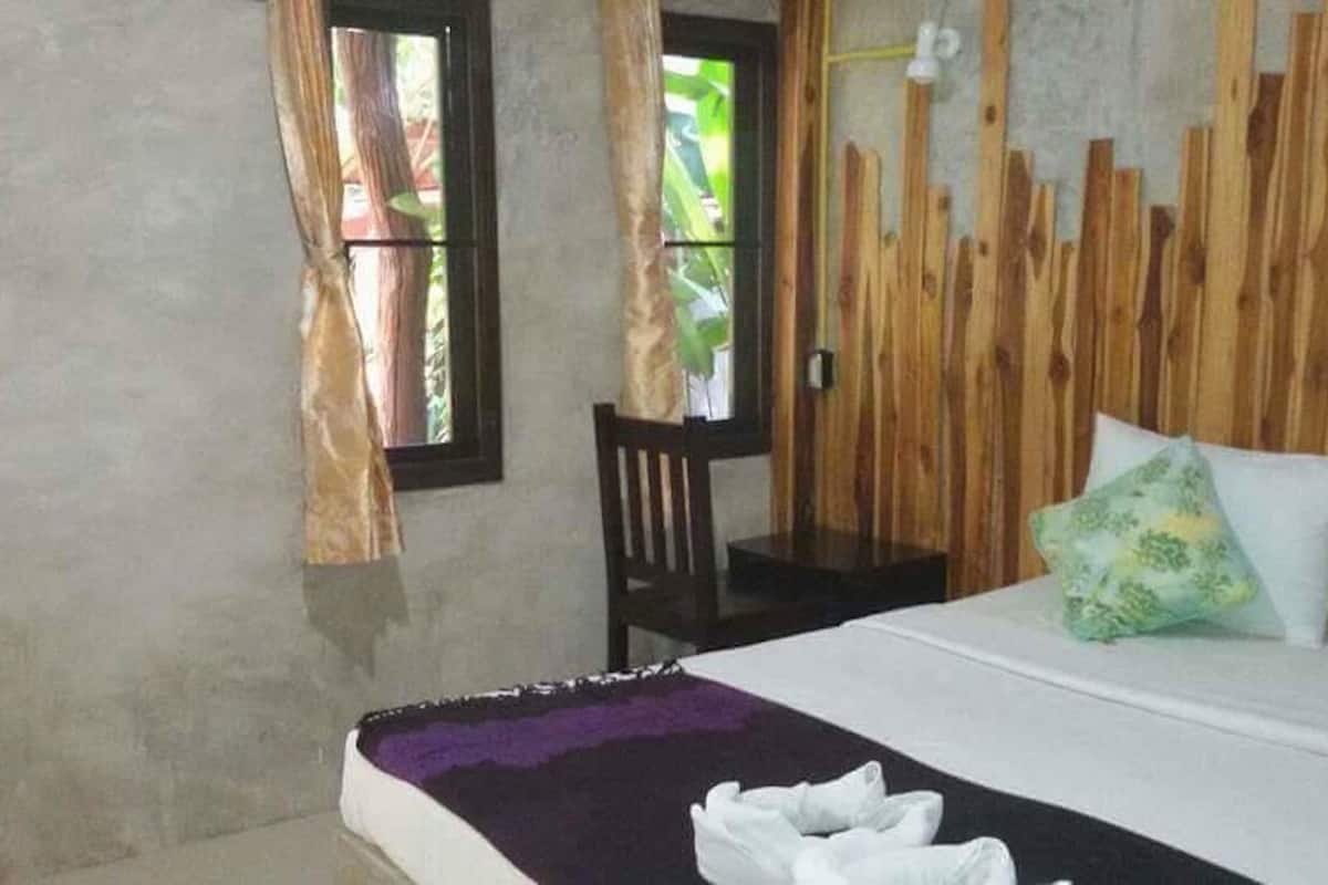 Ein Zimmer mit einem Bett, einem Stuhl und einer Holzwandverkleidung.