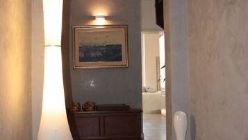 A hallway with a floor lamp, a painting on the wall, and a cabinet.