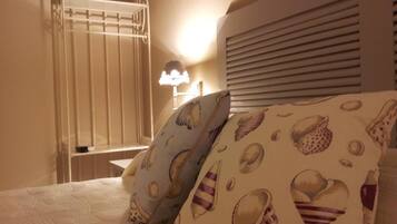 Een hotelkamer met een bed, nachtkastje, lamp en raam met zonwering.