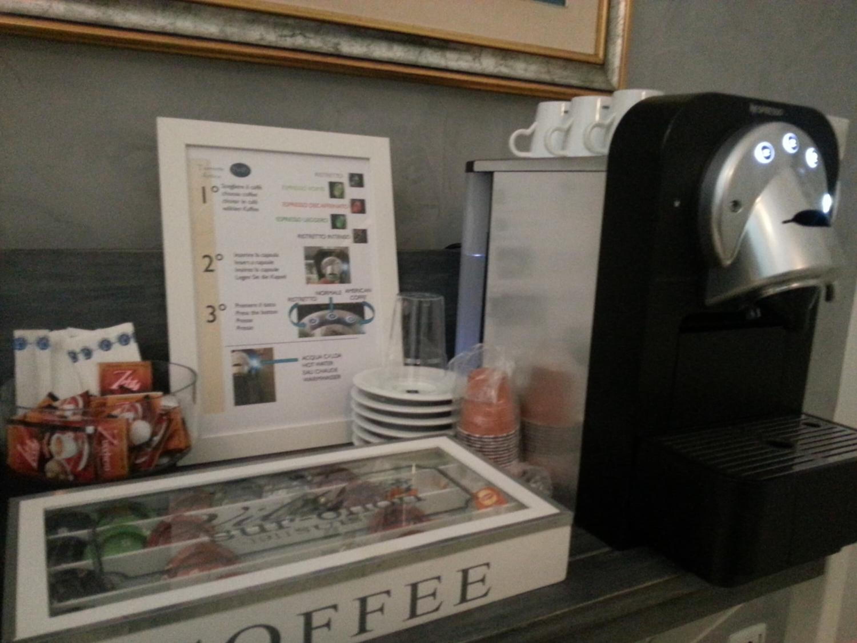 A coffee station with a menu board, coffee machine, and disposable cups.