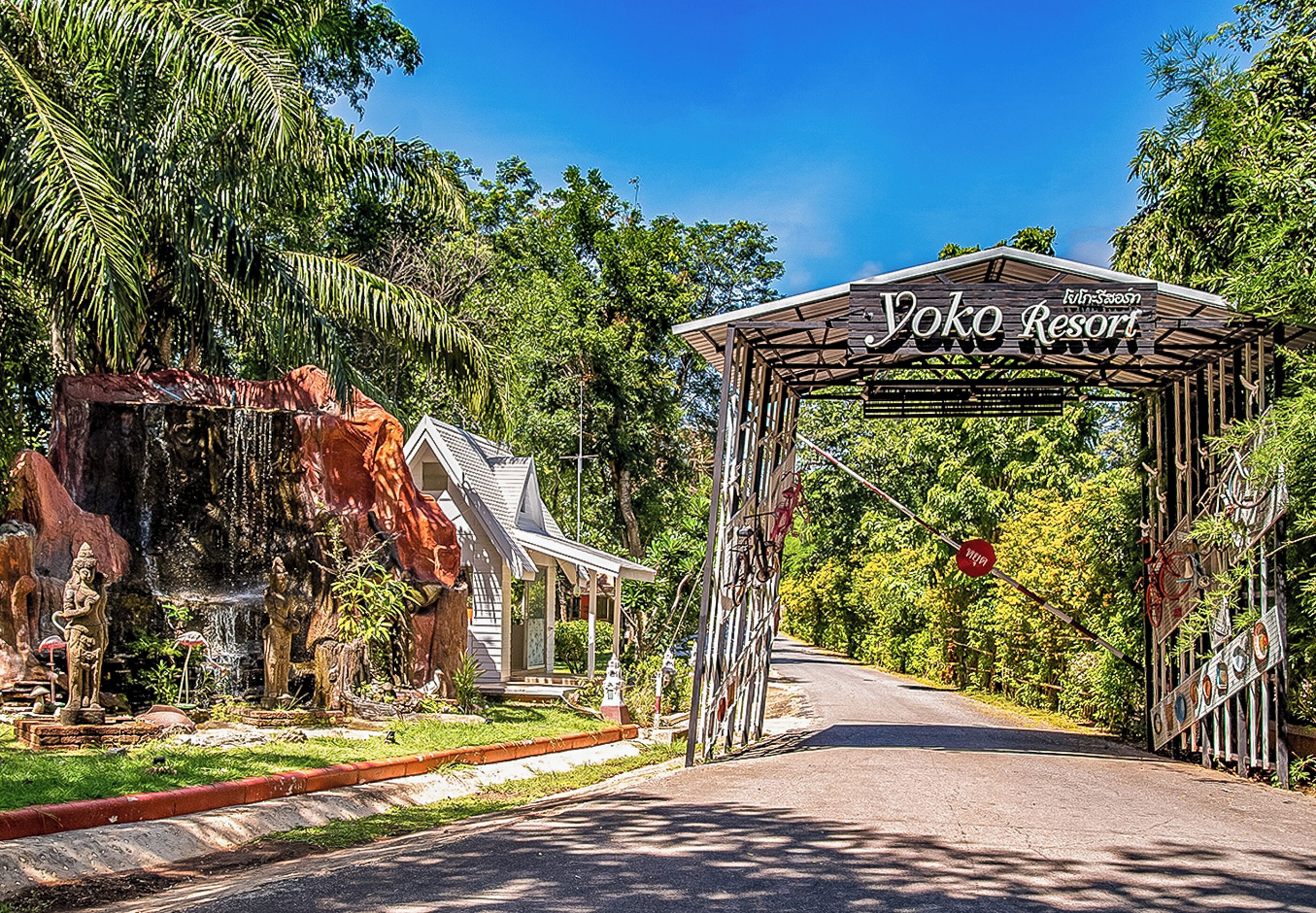 Une enseigne indiquant l’entrée du Yoko Resort, avec un porche et un petit bâtiment situé à gauche.