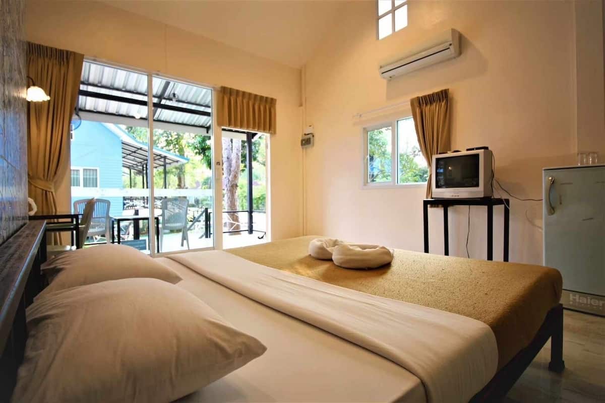A hotel room with a bed, a TV on a stand, and a refrigerator.