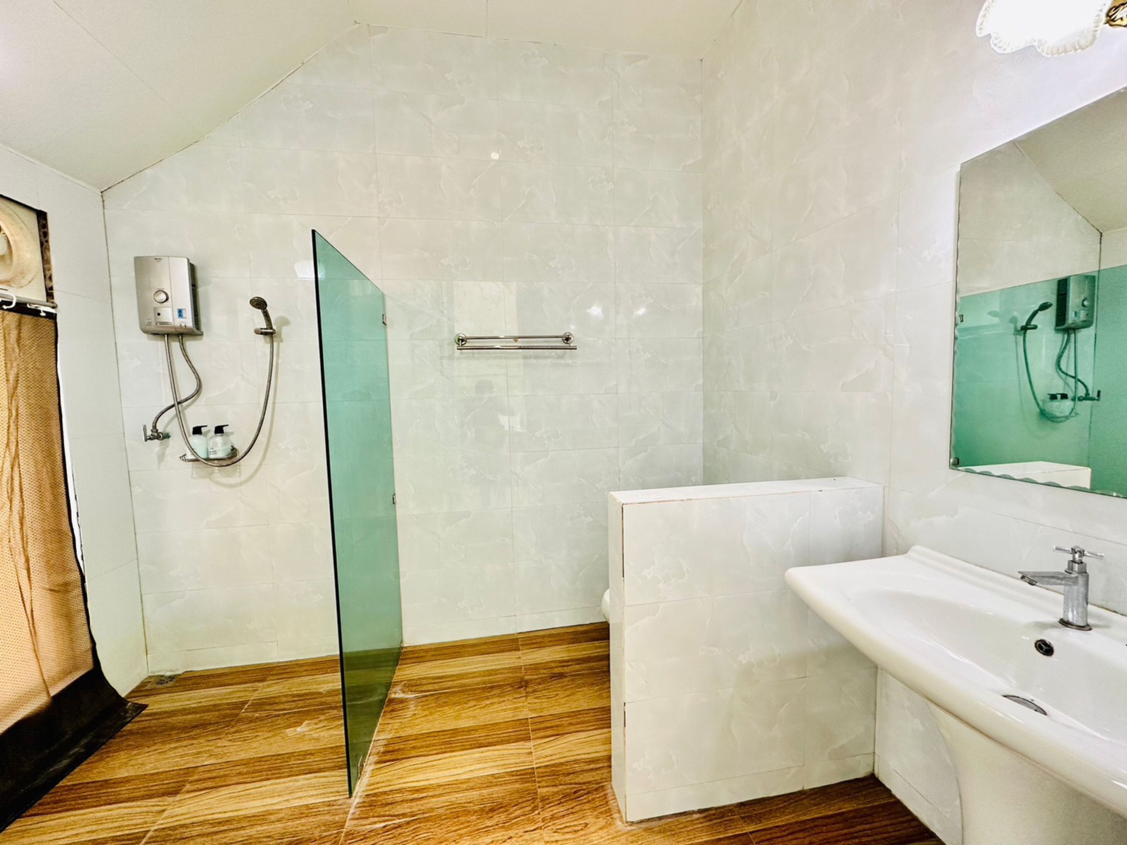 A modern bathroom with a glass shower enclosure, a white sink, and a large mirror.