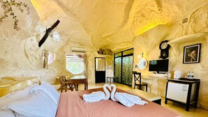 Una habitación acogedora con cama, escritorio, silla, televisor y un refrigerador pequeño.
