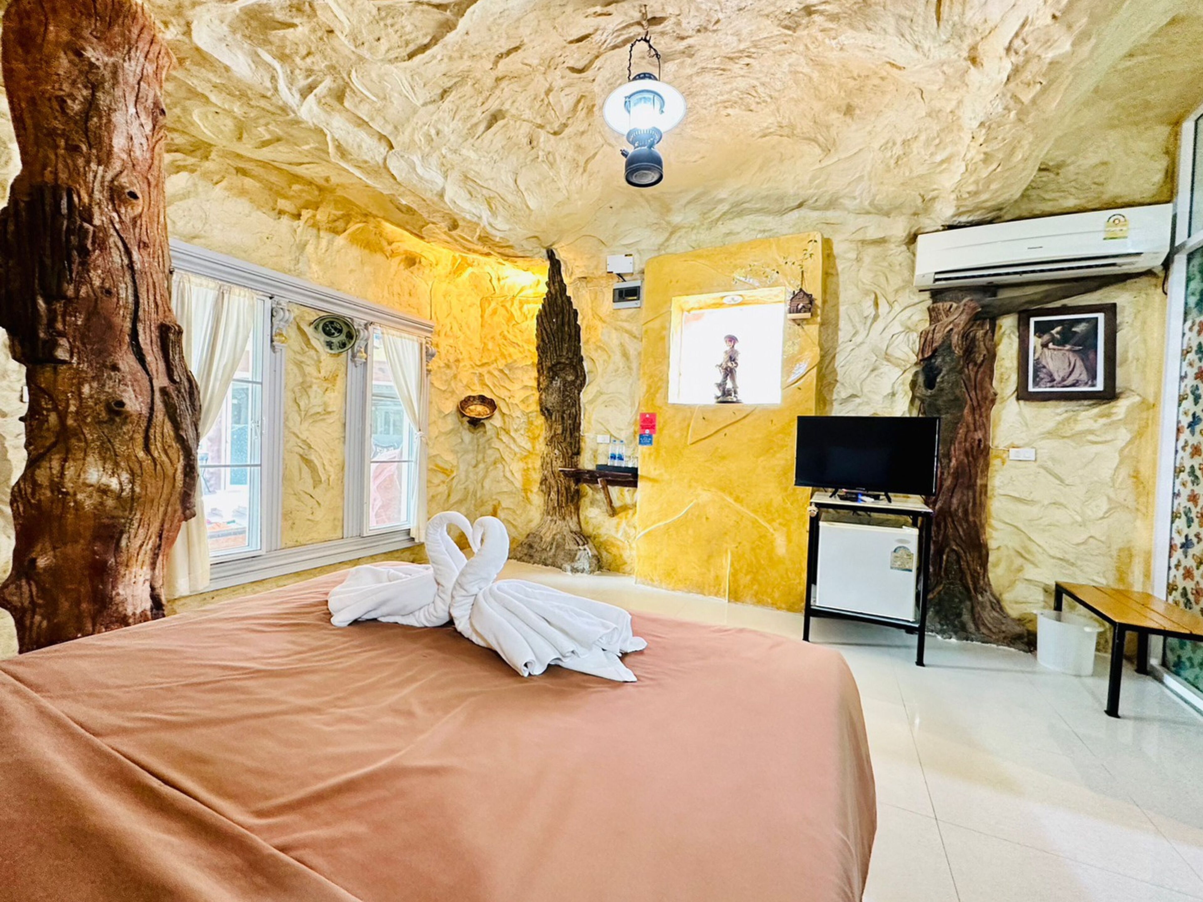 A room with a bed, a television, a small table, and a wall-mounted air conditioner.