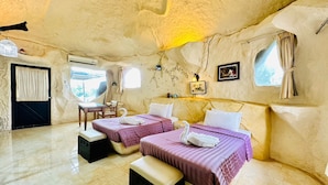 Una habitación con dos camas, una mesita y una silla.