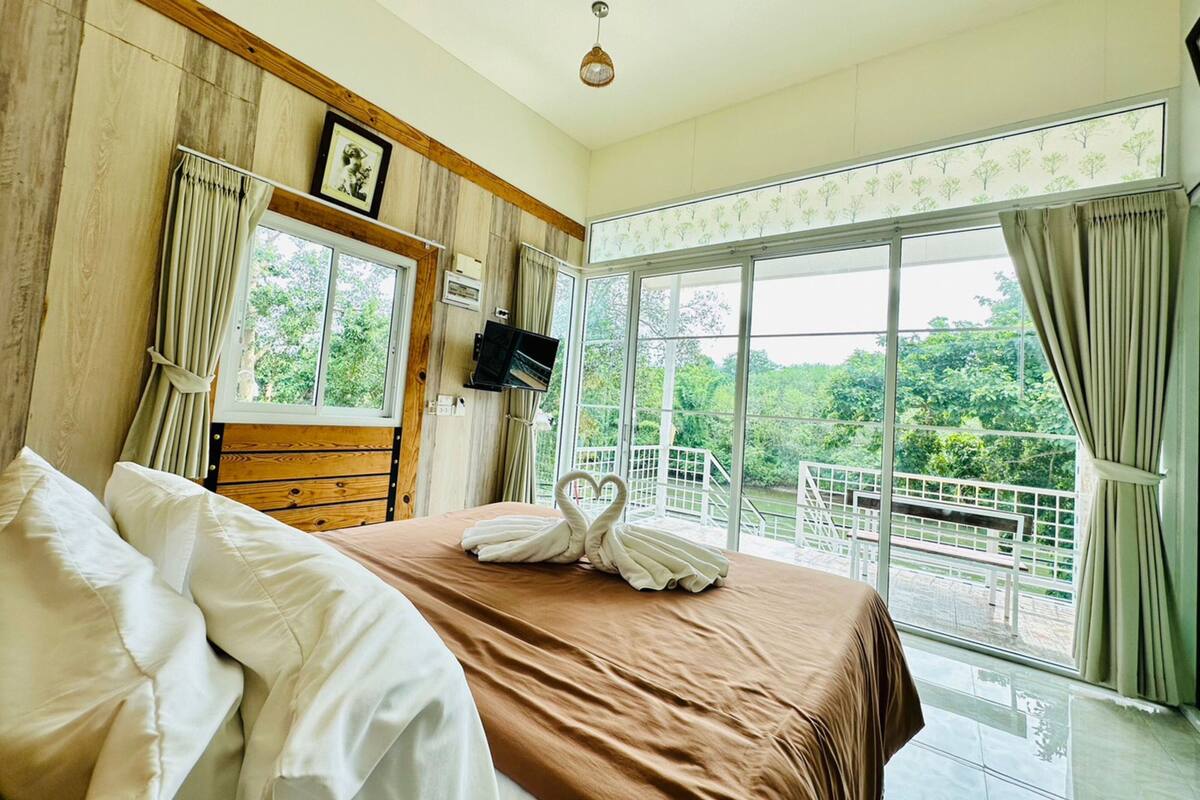 A bedroom with a bed, a TV, and a balcony with a railing.