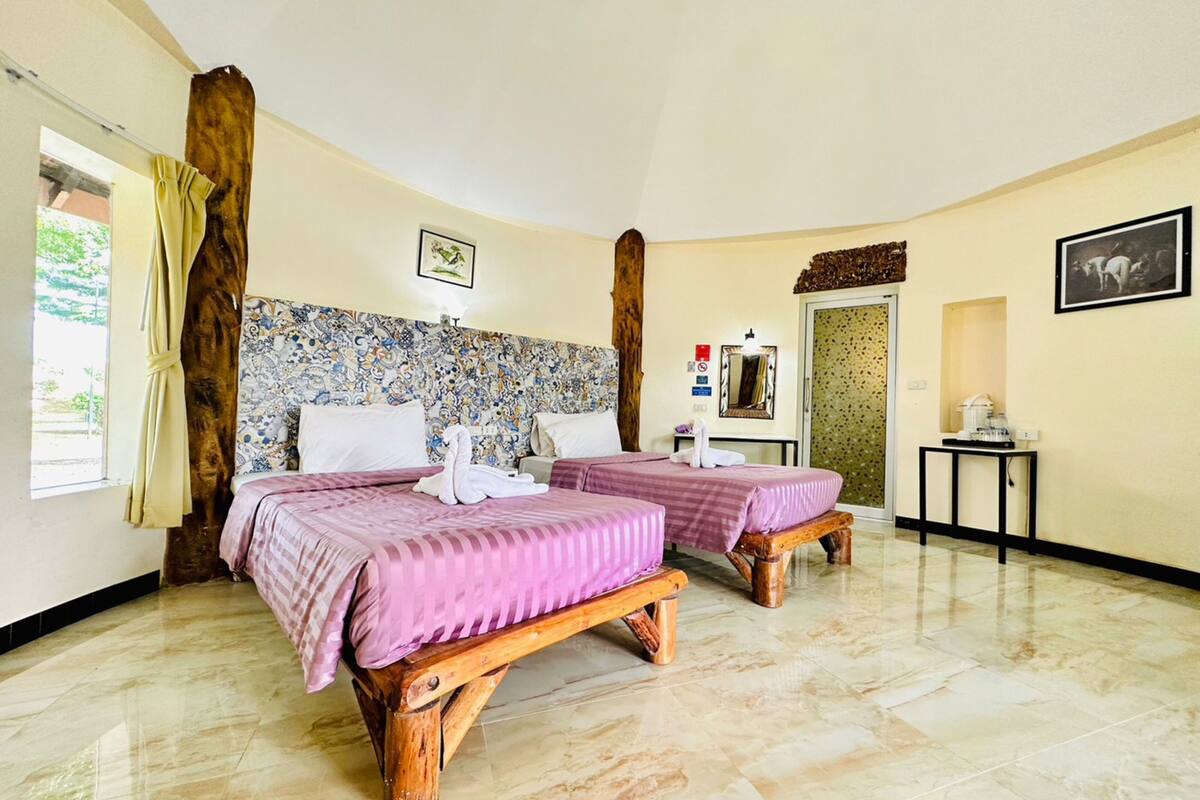 A hotel room with two beds, a wooden headboard, a small table, and a mirror.
