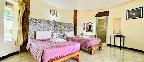 Una habitación de hotel con dos camas, un cabecero de madera, una mesita pequeña y un espejo.