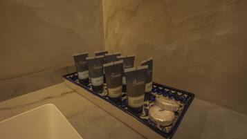 A bathroom with a marble sink and a tray holding several bottles of shampoo conditioner.