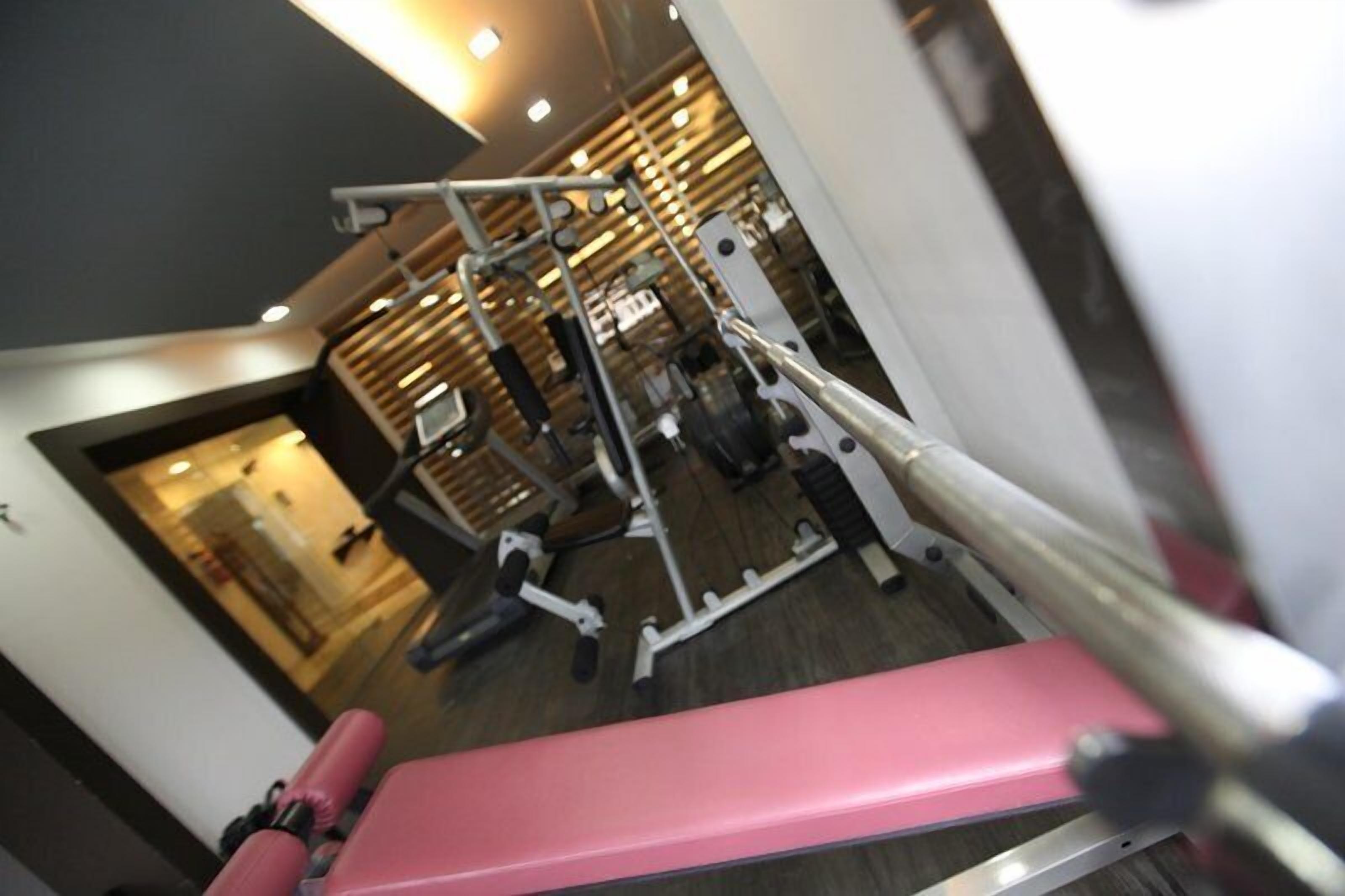 Un gimnasio con una banca rosa y diverso equipo de ejercicio.