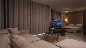 A modern hotel room with a large bed, a sofa, a TV, and a lamp. - Ankars Suites & Hotel (Ramallah)