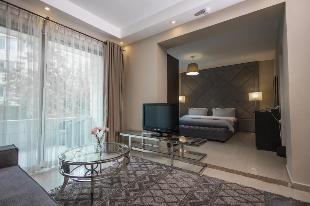 A modern hotel room with a bed, television, and a glass coffee table.