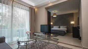 A modern hotel room with a bed, television, and a glass coffee table.